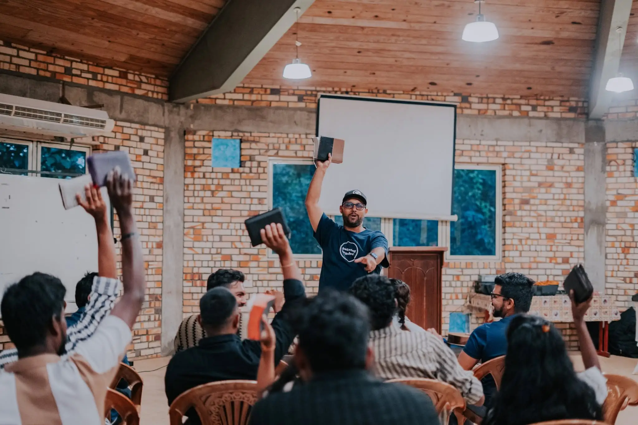 Hands raised holding open books during a gathering
