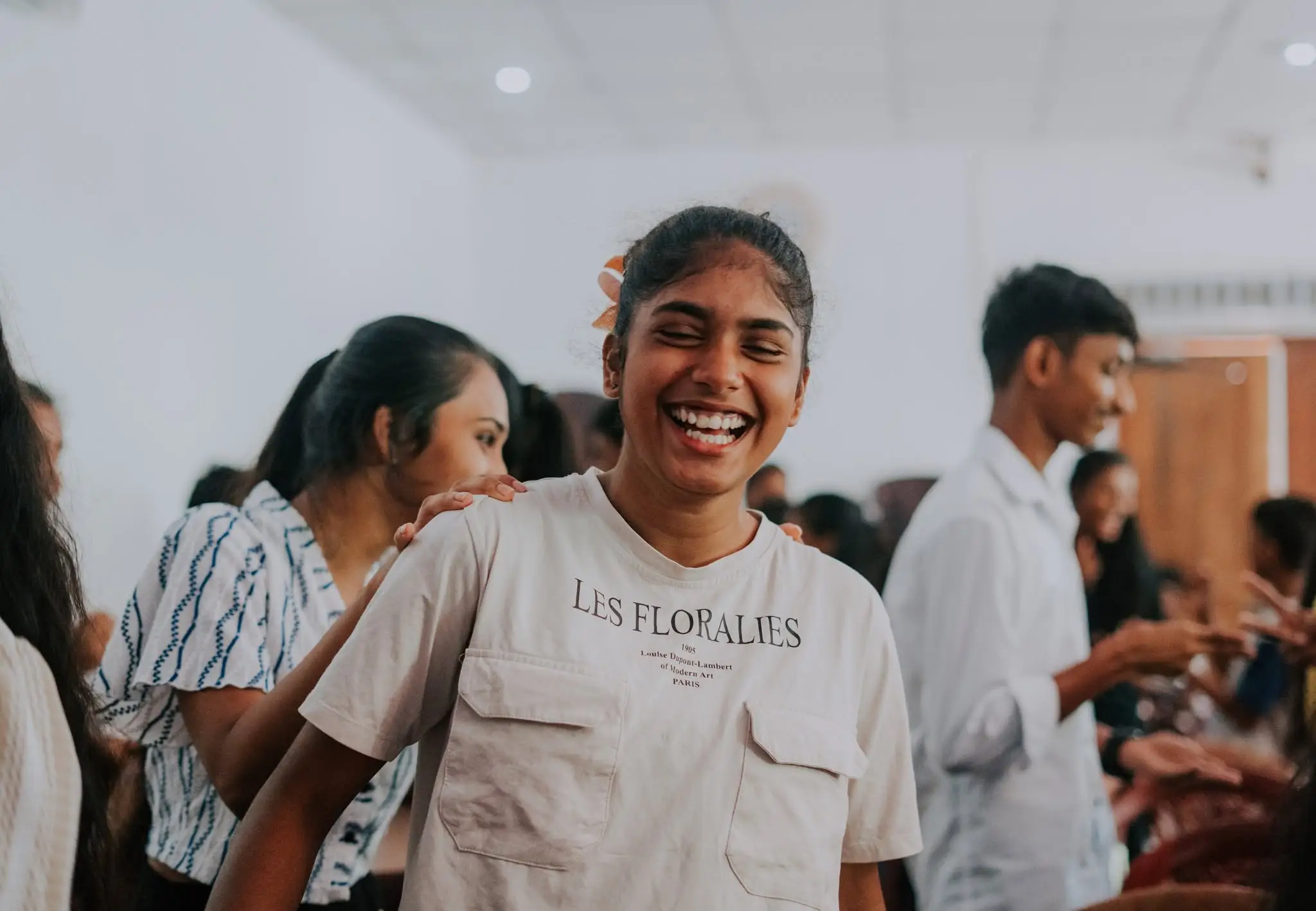 A young woman laughing among a crowd after a gathering